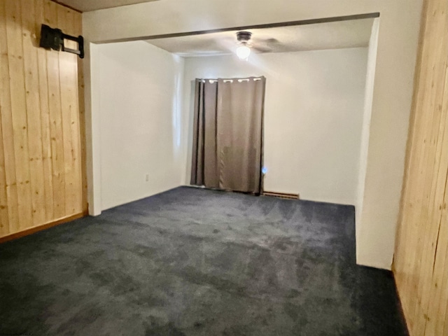 carpeted spare room with ceiling fan and wooden walls