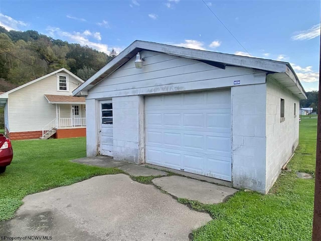 garage with covered porch and a yard