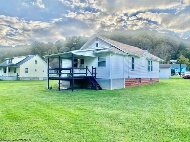 back of house featuring a lawn and a deck