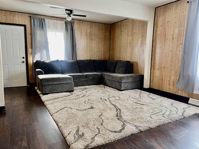 living room with ceiling fan, dark hardwood / wood-style flooring, and wooden walls