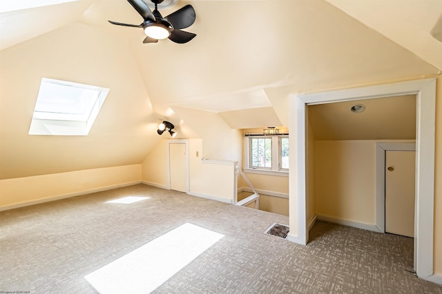 additional living space featuring carpet flooring, lofted ceiling with skylight, and ceiling fan