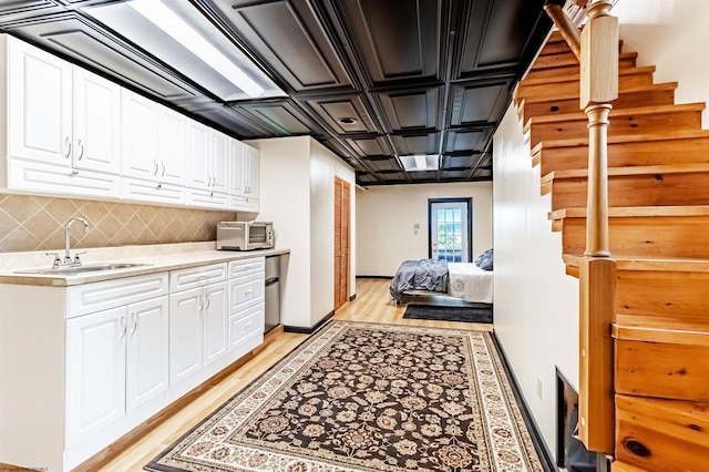 kitchen featuring backsplash, light hardwood / wood-style floors, white cabinetry, and sink