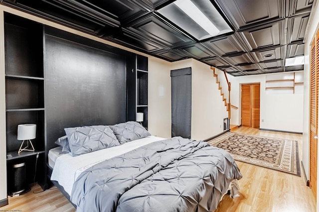 bedroom featuring coffered ceiling and light hardwood / wood-style flooring