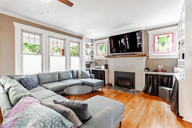 living room featuring a fireplace, light hardwood / wood-style flooring, ceiling fan, and ornamental molding