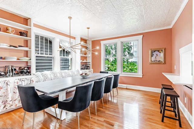 dining room with a textured ceiling, light hardwood / wood-style floors, crown molding, and a chandelier