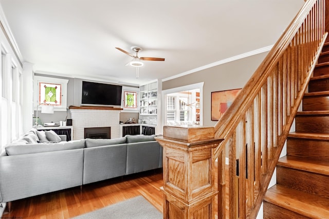 living room featuring a fireplace, ceiling fan, hardwood / wood-style floors, and ornamental molding