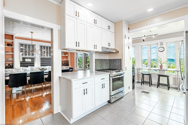 kitchen featuring white cabinets, appliances with stainless steel finishes, light hardwood / wood-style floors, and hanging light fixtures