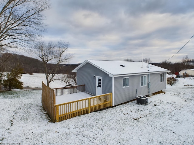 snow covered rear of property featuring cooling unit and a wooden deck