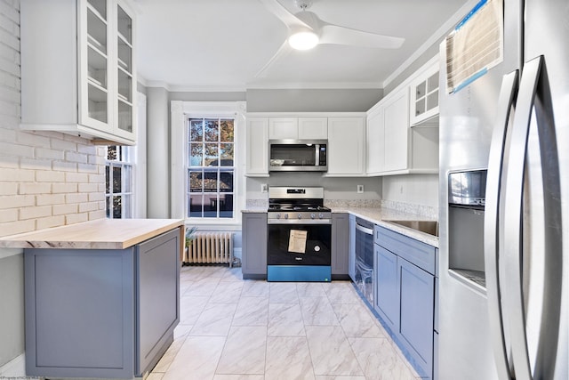 kitchen with wood counters, radiator heating unit, stainless steel appliances, and white cabinetry