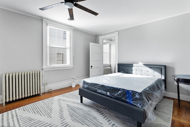 bedroom featuring ceiling fan, wood-type flooring, ornamental molding, and radiator