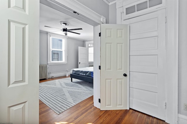 bedroom featuring ceiling fan, dark hardwood / wood-style flooring, radiator heating unit, and crown molding