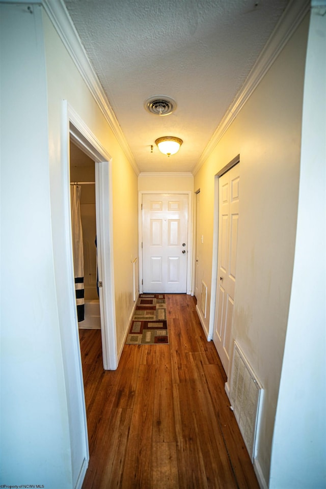 hallway with dark hardwood / wood-style flooring, a textured ceiling, and ornamental molding