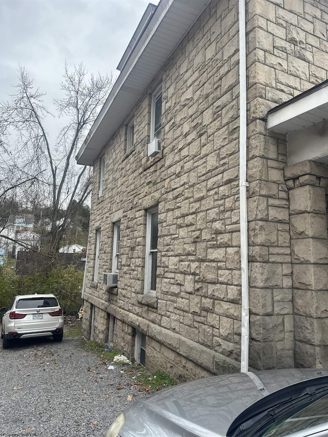 view of side of home featuring cooling unit and stone siding