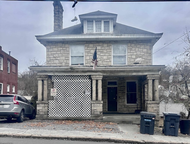 traditional style home featuring covered porch and stone siding