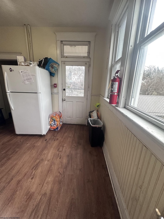 interior space featuring a healthy amount of sunlight, wood finished floors, and wainscoting