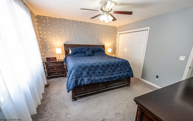 bedroom with a textured ceiling, a closet, ceiling fan, and light colored carpet