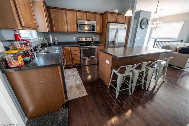 kitchen featuring an inviting chandelier, sink, dark hardwood / wood-style floors, appliances with stainless steel finishes, and a kitchen island