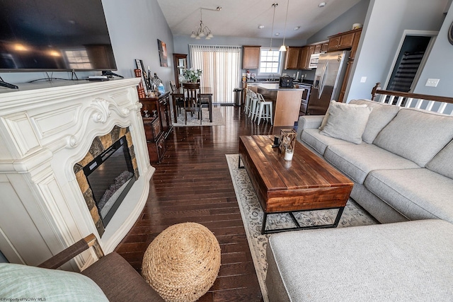 living room with dark hardwood / wood-style floors, a chandelier, and vaulted ceiling