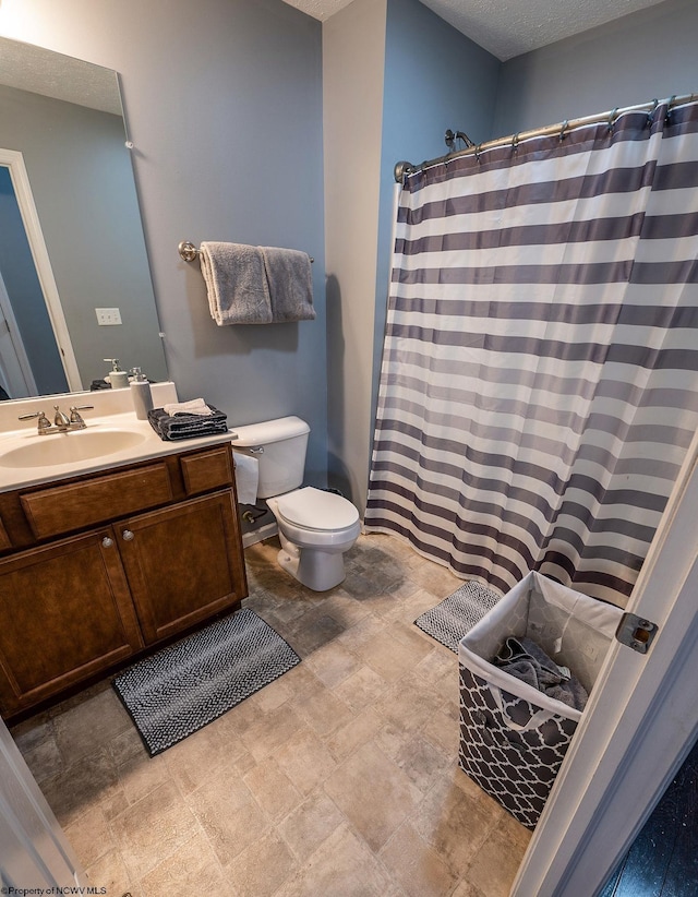 bathroom featuring vanity, a textured ceiling, and toilet