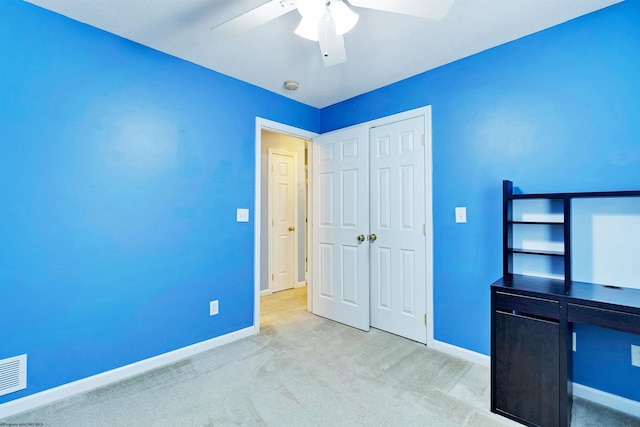 unfurnished bedroom with ceiling fan, a closet, and light colored carpet