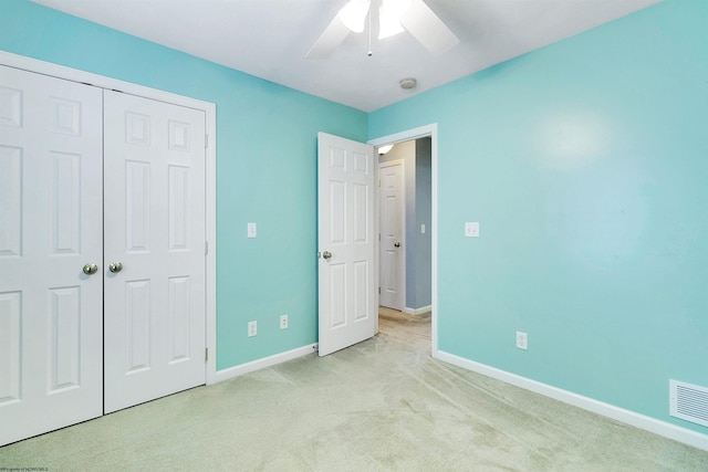 unfurnished bedroom with a closet, light colored carpet, and ceiling fan