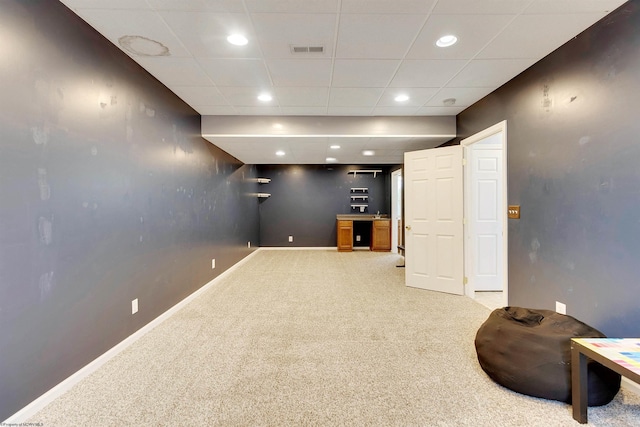 basement featuring light carpet and a drop ceiling