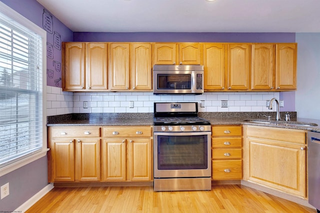 kitchen with decorative backsplash, stainless steel appliances, light hardwood / wood-style flooring, and sink