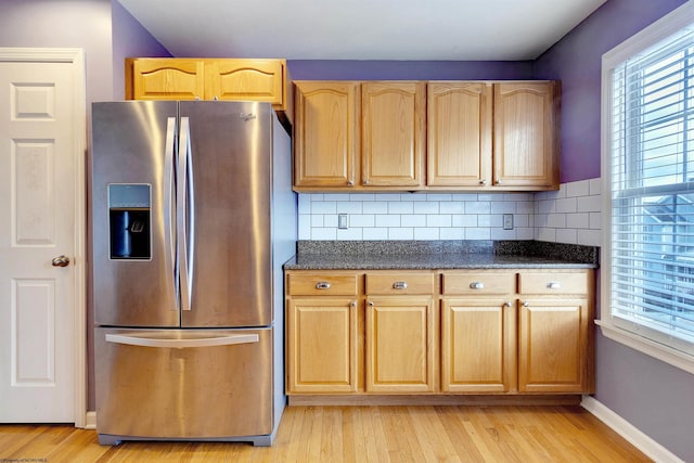 kitchen with stainless steel refrigerator with ice dispenser, light hardwood / wood-style floors, and tasteful backsplash