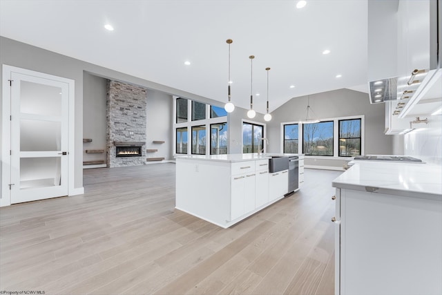 kitchen featuring a spacious island, white cabinetry, decorative light fixtures, and light stone counters