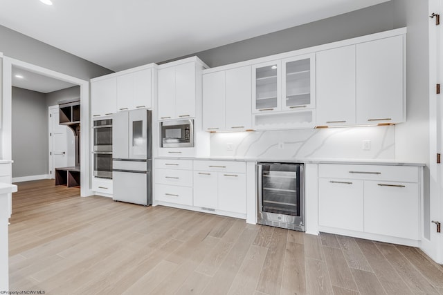 kitchen with wine cooler, light wood finished floors, stainless steel appliances, glass insert cabinets, and white cabinetry