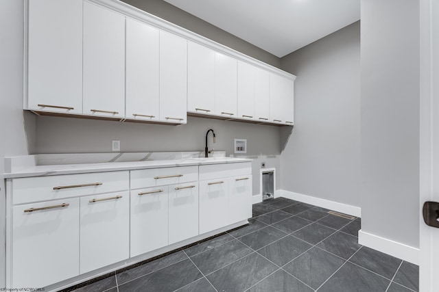 laundry room featuring hookup for a washing machine, a sink, baseboards, cabinet space, and electric dryer hookup