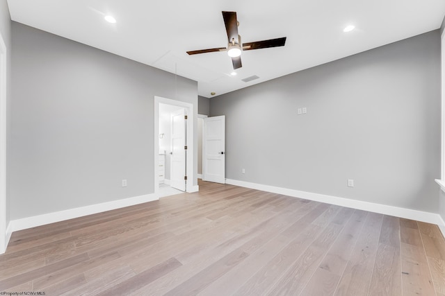 unfurnished bedroom featuring visible vents, attic access, light wood-style floors, connected bathroom, and baseboards