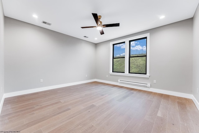 unfurnished room featuring a baseboard heating unit, baseboards, visible vents, and light wood-style floors