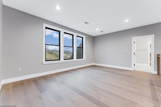 empty room with light wood-style flooring, visible vents, baseboards, and recessed lighting