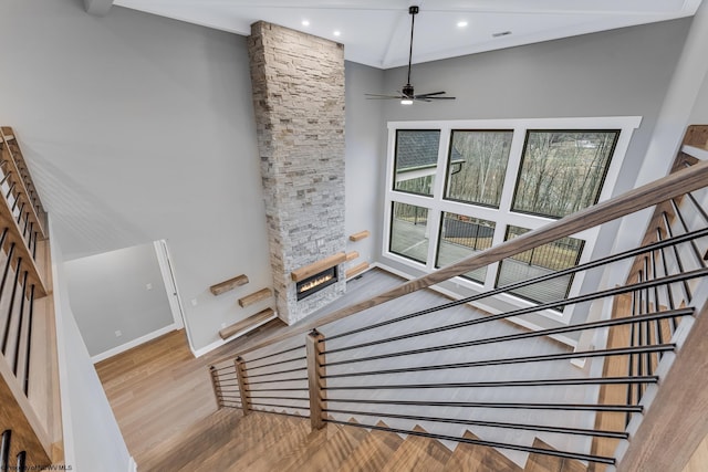 stairway featuring recessed lighting, a ceiling fan, a stone fireplace, wood finished floors, and baseboards