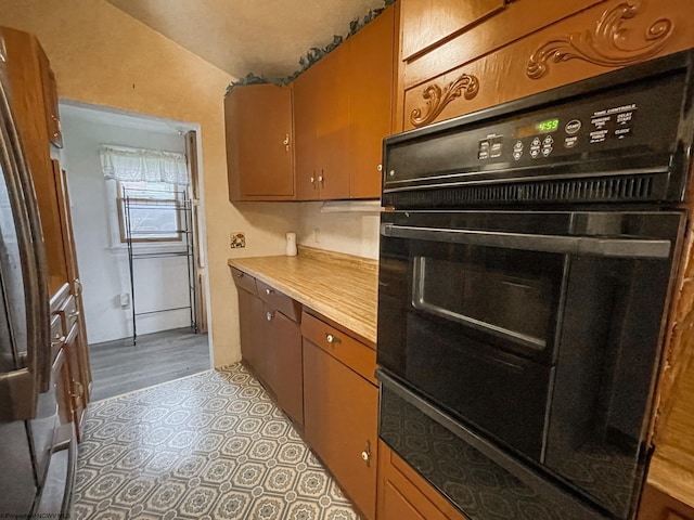 kitchen featuring vaulted ceiling, light hardwood / wood-style floors, and black oven