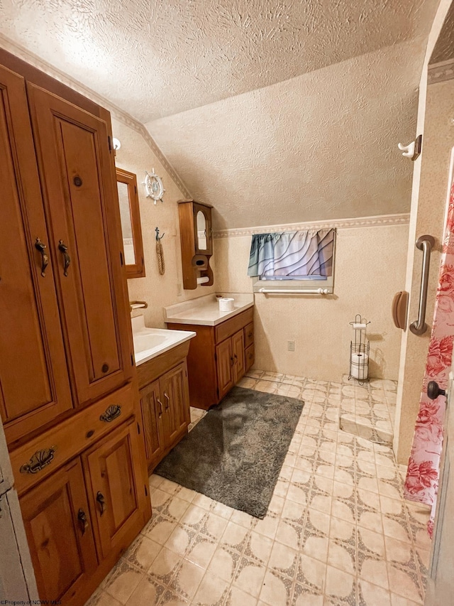 bathroom featuring vanity, a textured ceiling, and vaulted ceiling