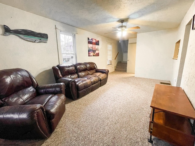 carpeted living room with ceiling fan and a textured ceiling