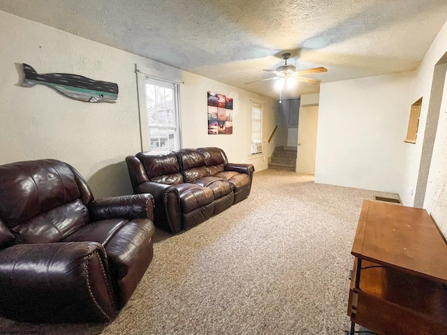 living room with ceiling fan, carpet floors, and a textured ceiling