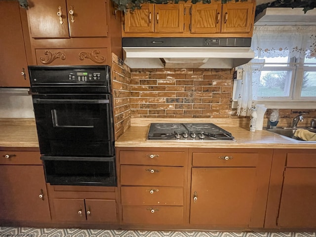 kitchen featuring tasteful backsplash, oven, stainless steel gas cooktop, and sink