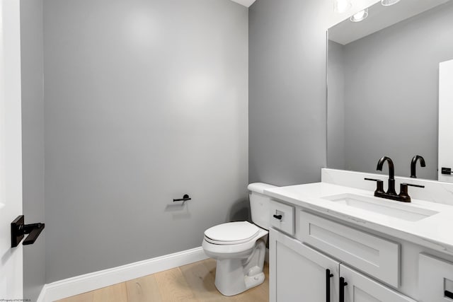 bathroom with hardwood / wood-style flooring, vanity, and toilet