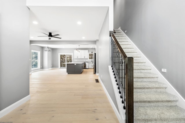 stairway with hardwood / wood-style floors and ceiling fan