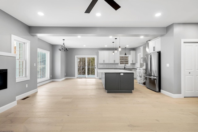 kitchen featuring white cabinetry, a center island, hanging light fixtures, light hardwood / wood-style flooring, and stainless steel refrigerator