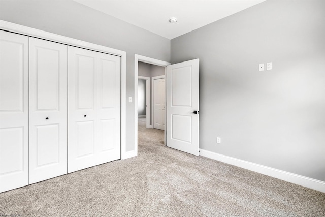 unfurnished bedroom featuring light colored carpet and a closet