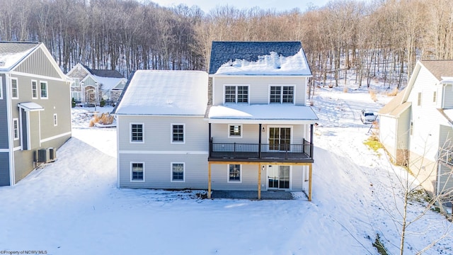 snow covered rear of property featuring cooling unit