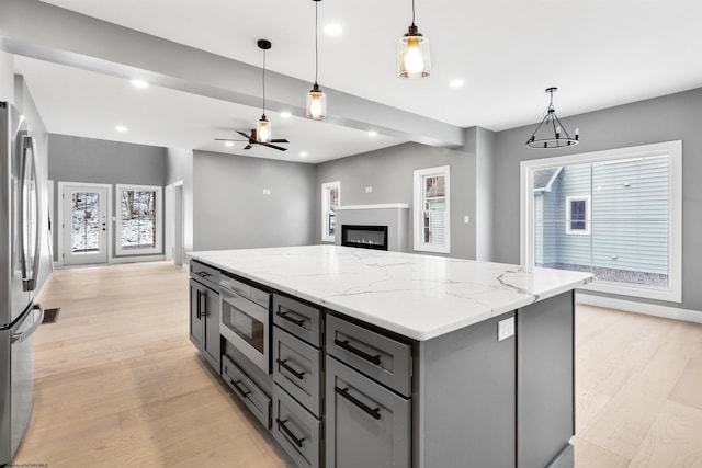 kitchen with pendant lighting, stainless steel appliances, a kitchen island, and gray cabinetry