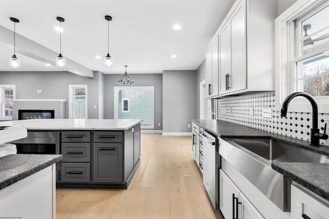 kitchen featuring sink, white cabinetry, gray cabinetry, decorative light fixtures, and stainless steel dishwasher