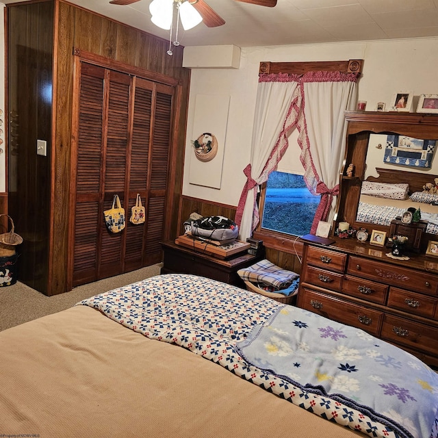 bedroom with ceiling fan, a closet, carpet floors, and wood walls