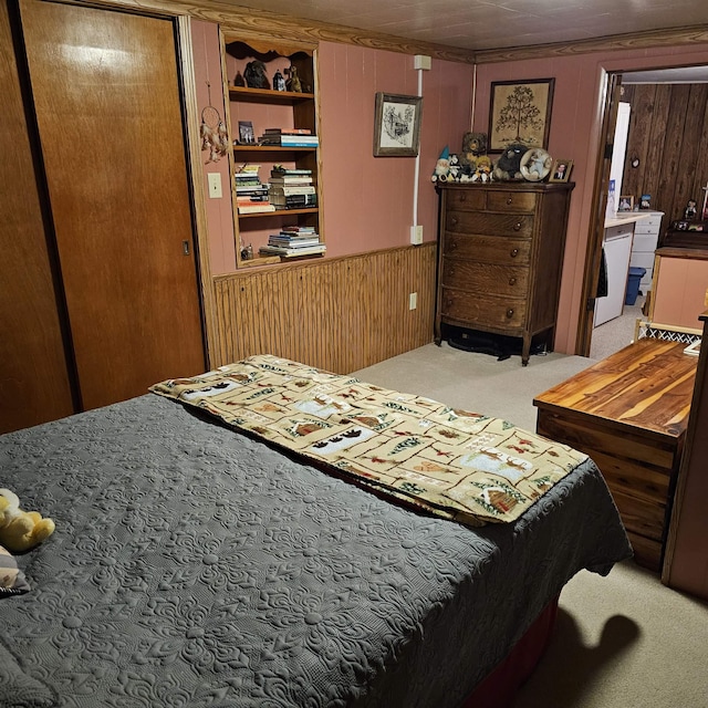 bedroom with a closet, light carpet, and wooden walls