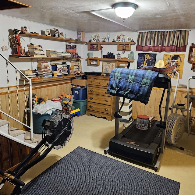 exercise room with a textured ceiling and wood walls